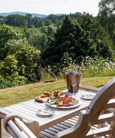 Un tavolo e una panchina seduti in un giardino, cibo e bevande sul tavolo