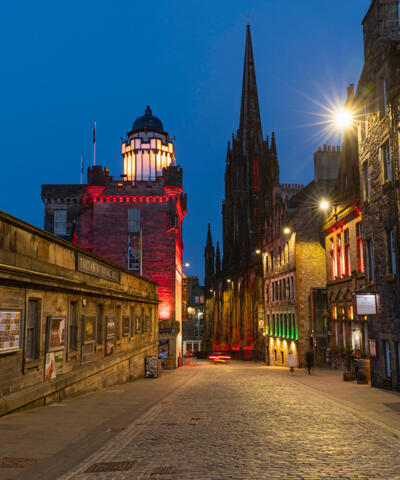 Looking down the Royal Mile across the cobbled street, buildings on both sides, some lit up, all at night